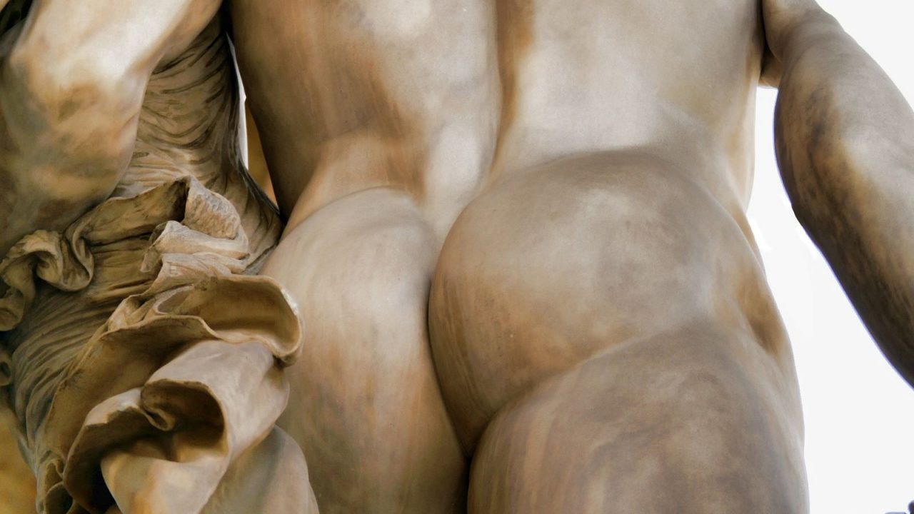 En ljust bronsfärgad statys, bakifrån, aptitlig rumpa i blickfånget.